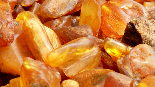 Close-up of raw amber stones in various shades of yellow, orange, and brown.