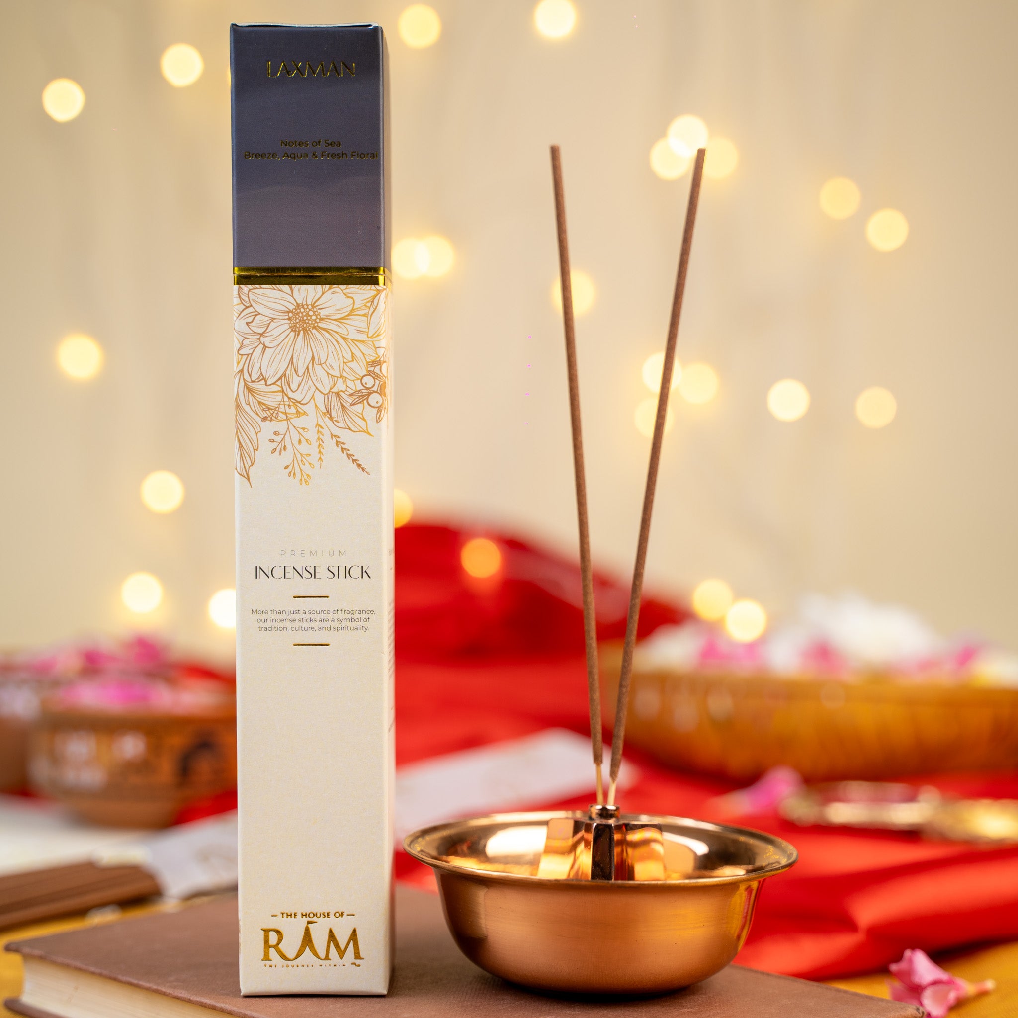 Premium incense stick packaging labeled "laxman" with notes of sandalwood and oud, placed beside a copper incense holder with two incense sticks