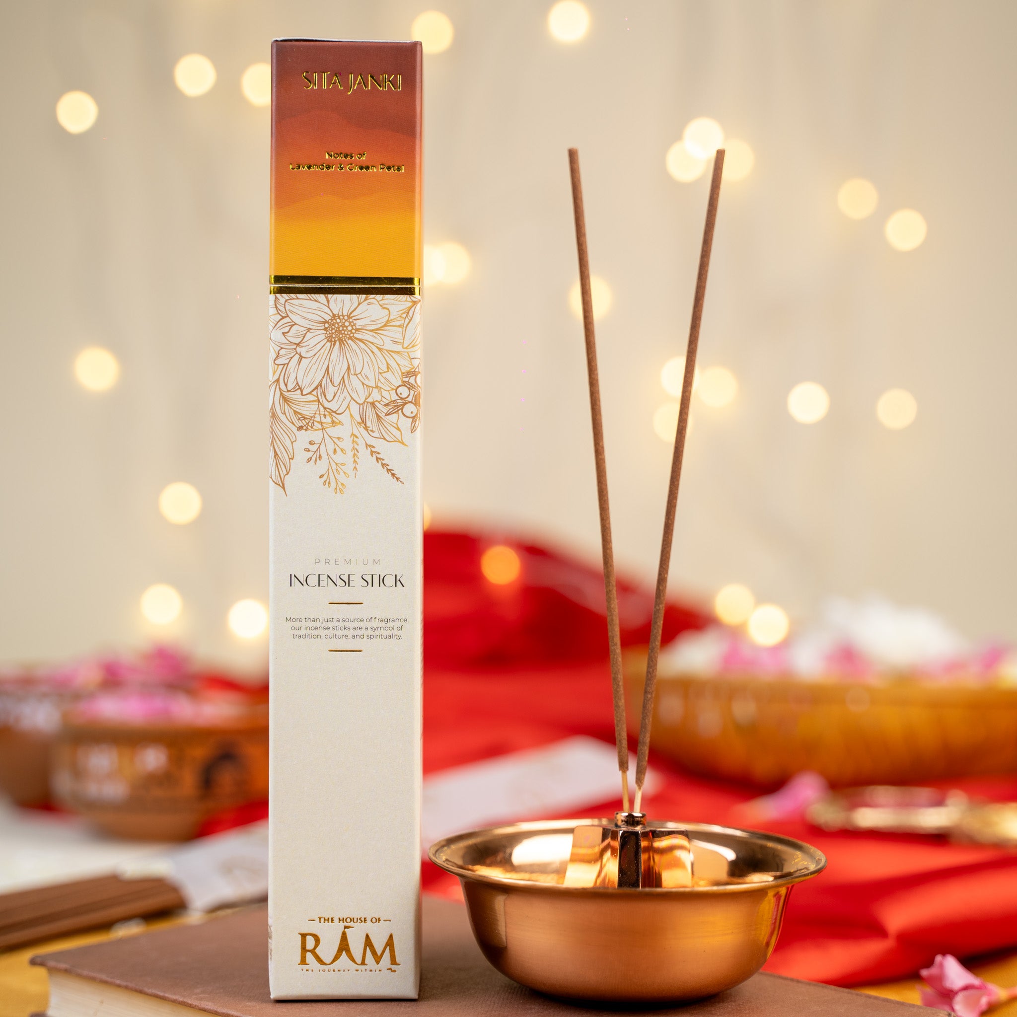 Premium incense stick packaging labeled "sitajanki" with notes of sandalwood and oud, placed beside a copper incense holder with two incense sticks